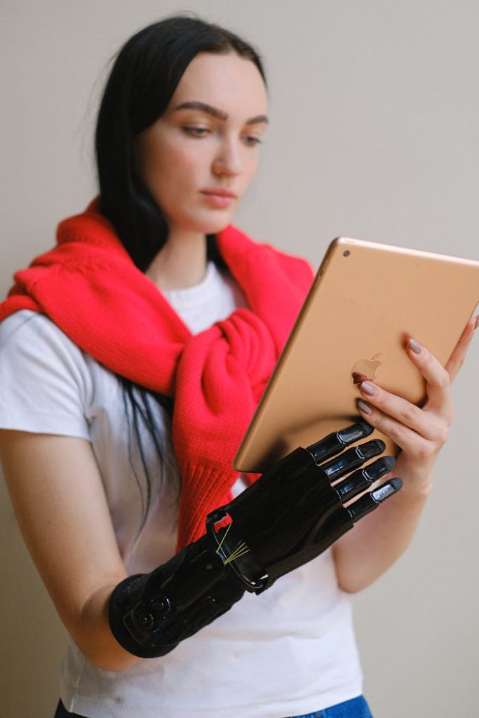 A woman with a prosthetic arm engages with a digital tablet indoors.